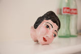 Side view of a mid-century ceramic head sculpture with a prim, painted expression.