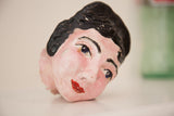Close-up, angled view of the mid-century ceramic head's painted face with red lips.