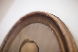The naturally distressed and aged patina on the early 20th-century portrait frame.
