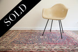 Antique Persian Kerman rug pairing traditional design with a modern tan armchair.
