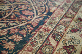 Angled close-up of the antique Kerman rug's mellow floral design and time-softened wool pile.