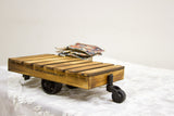 A miniature wooden industrial cart showing its torched pine finish, stamped side, and black wheels.