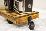 Black swivel caster wheel on the torched pine frame of a decorative mini cart.