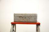 Vintage gray metal tool box with a rusty, weathered finish and a front keyhole.