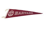 Detail of Harvard pennant, showing white shield emblem and outline lettering on red felt.