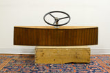 Vintage 1940s wooden boat helm featuring a curved slatted design and black wheel.