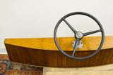 Black DUOTROL steering wheel on the planked wooden vintage boat helm.