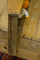 Vintage wooden boat helm's weathered side edge, with exposed screws and a metal eye-hook.