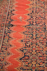 Angled detail of 4x6 antique Malayer rug with red lozenge medallion and dark blue Herati pattern.