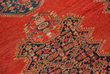 Small patch and wear detail on antique tomato red Malayer rug with dark blue medallion.