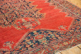 Angled close-up of the tomato red field and navy blue Herati motif on a 4x6 antique Malayer rug.