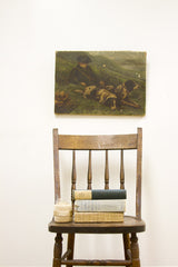 Antique painting of boy, two dogs, green landscape, showing aged canvas edges.