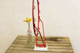 Industrial accent's chippy red metal hoop base secured to white wood with bolts.