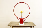 Upper right curve of the chippy bright red metal basketball hoop.