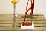 Chippy red metal base bolted to its white wooden stand.