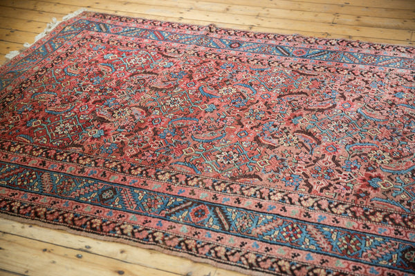 Angled view of a 5x13 antique Bakshaish rug showing the faded herati pattern and Caucasian-style floral borders.