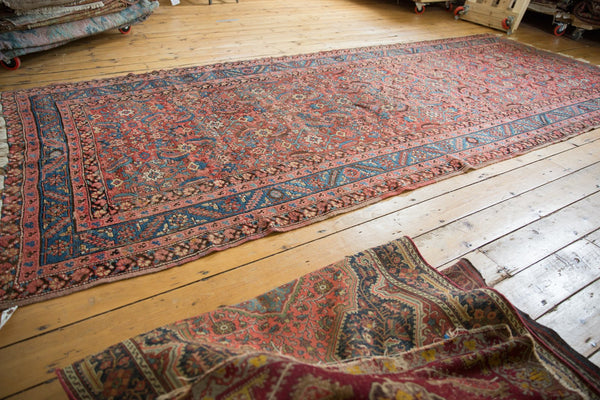 Long angled view of an antique Persian Bakshaish rug showcasing its rust-red herati pattern.