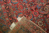 Antique Persian Bakshaish rug with corner folded back to show the woven foundation and white fringe.