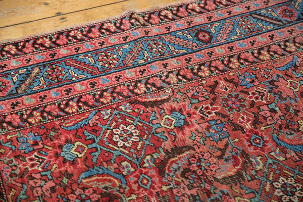Detail of the elaborate blue and red border with Caucasian floral motifs on an antique Persian rug.