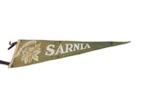 Angled view of a vintage green felt Sarnia Canada pennant with cream lettering and maple leaves.