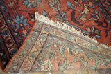 Shabby vintage Lilihan rug corner, revealing faded cranberry floral pile and intricate woven back.