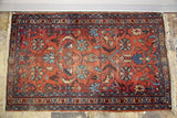 Shabby vintage Lilihan Persian rug corner, with faded cranberry florals and worn fringe.