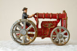 Red Fordson cast iron toy tractor with grey wheels, rust, and chippy paint.