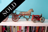 Vintage cast iron horse and buggy with red tractor toy, showing aged patina.