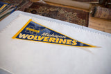 Vintage Michigan Wolverines pennant laid flat next to a ruler for scale.