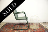 Green metal chair base with white wire birdcage on a Persian Lilihan rug.