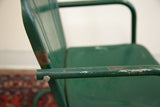Kids metal tulip chair's green armrest, showcasing rust and aged paint patina.