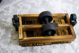Angled view of the mini cart's rustic wooden base with black metal casters and wheels.