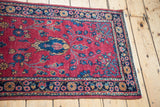 Vintage Sarouk runner corner with cranberry field, blue shadow medallion, floral border.