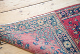 Folded corner of the Sarouk runner, showing re-selvedged edge and floral patterns in cranberry and blue.