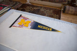Vintage Michigan University felt pennant laid out to show its full length and design.
