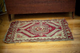 Antique Anatolian tribal rug, tattered central geometric medallion in ivory, red, minty blue.