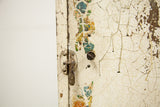 Close-up of the industrial cabinet's aged latch over chippy, floral-patterned paint.