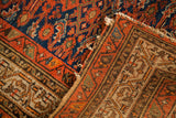 Vintage tribal Hamadan rug with tattered edge, rich indigo blue and red patterns.