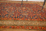 Vintage Hamadan tribal rug showing bold indigo and red pattern with its visibly tattered border.