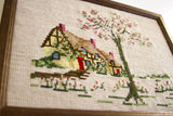 Vintage needlepoint artwork featuring green tree, pink blossoms, and textured stitches.