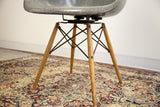 Eames PAW chair's aged birch wood dowel legs with visible markings, resting on an intricate floral patterned rug.