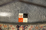 Zenith checkerboard sticker on elephant grey Eames fiberglass shell, showing fibrous swirls.