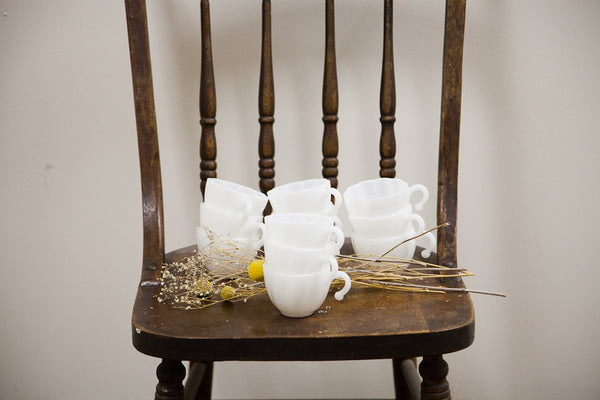 A collection of milk glass punch cups with a swirl design, arranged in stacks.
