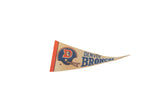 Vintage Denver Broncos felt pennant showing blue text, helmet logo, and aged tan texture.