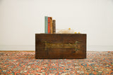 Antique hand-painted 'RASCAL IV' trunk with books on a vibrant Persian Hamadan rug.