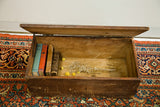 Open antique Rascal trunk interior with old books, dried flowers, and charming aged wood.