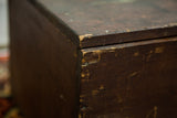 Distressed dark brown wood corner of the antique Rascal trunk, showing scratches and a nail.