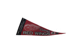 Close-up of Detroit Red Wings winged wheel logo on vintage red felt pennant.