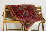 Intricate central floral design and plush pile on dark red Persian Sarouk rug.