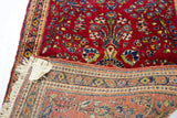 Plush dark red floral pile and visible hand-knotted foundation of a vintage Sarouk rug.